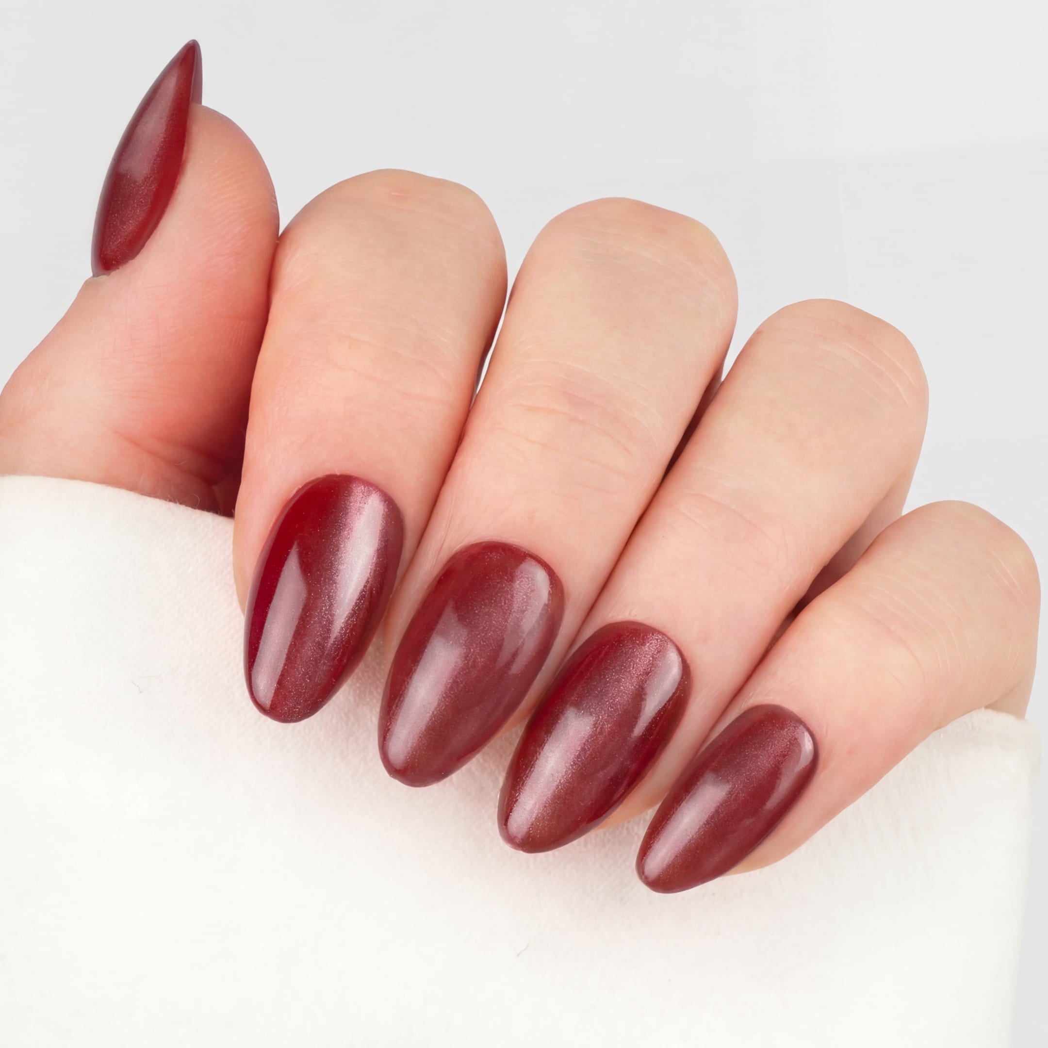 Cat Eye Ruby Almond press-on lösnaglar i almondform med djup röd nyans och skimrande cat eye-effekt