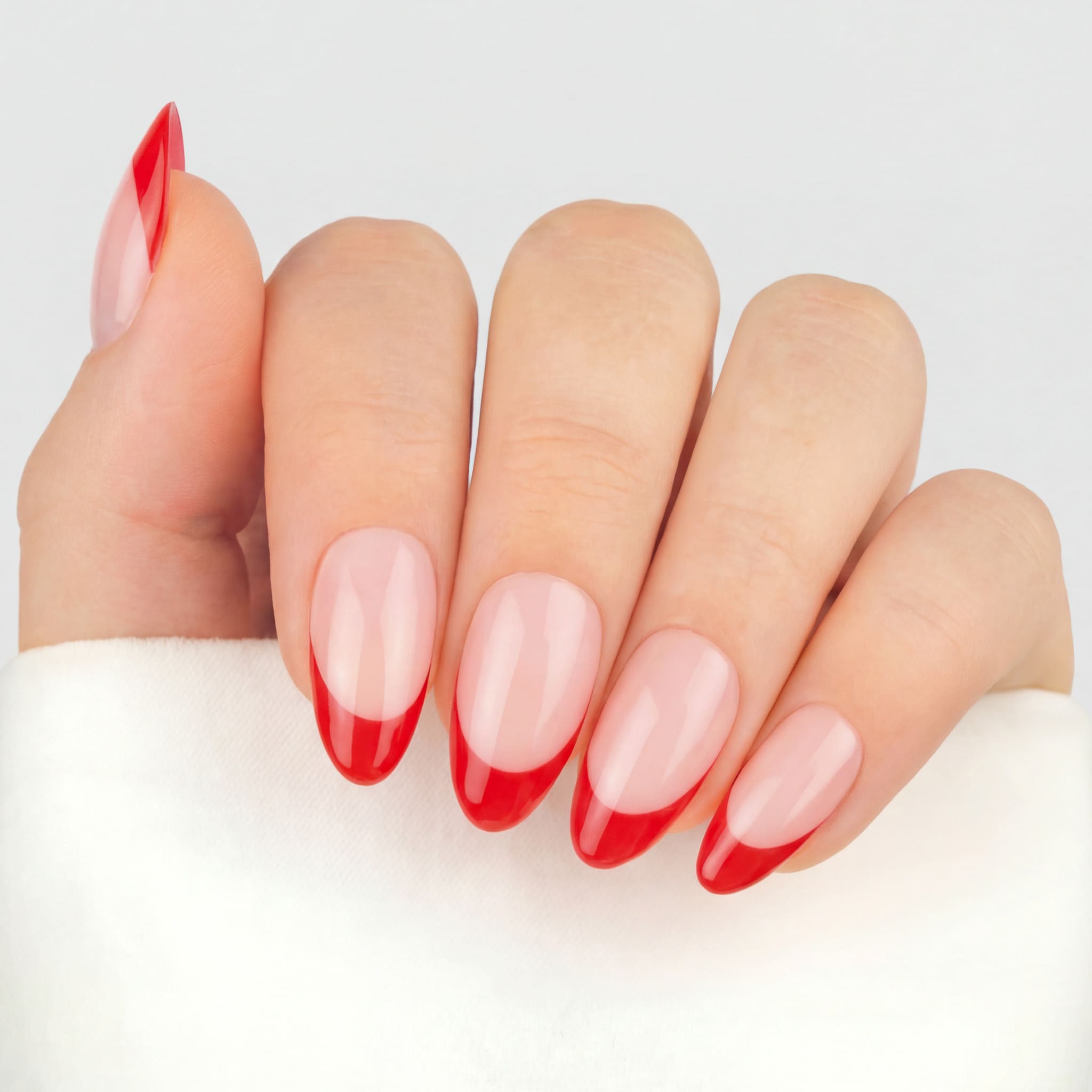 Press-on lösnaglar i almondform med röd fransk tipp och naturlig bas. Återanvändbara naglar som håller upp till 2 veckor med lim eller glue tabs.