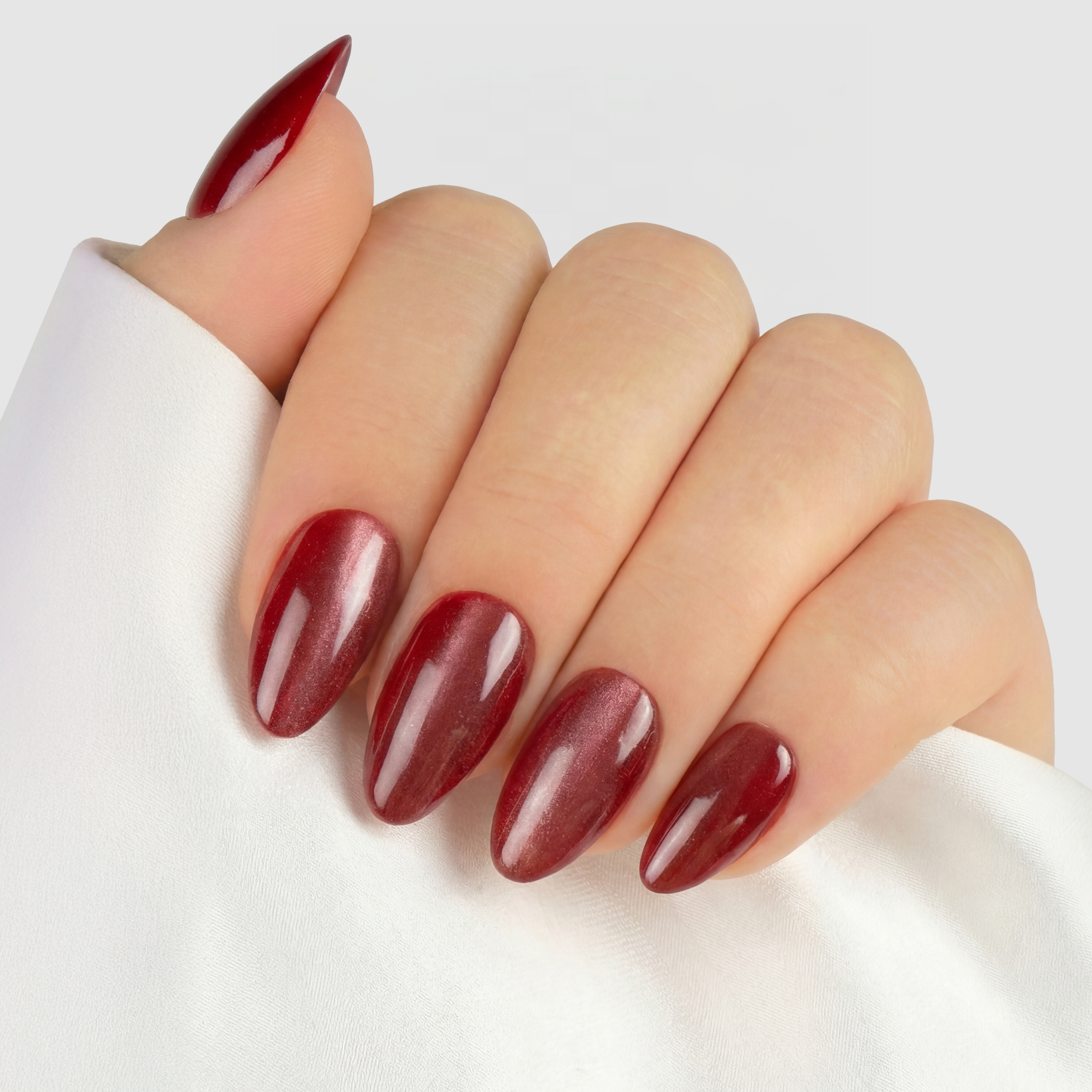 Cat Eye Ruby Almond press-on lösnaglar i almondform med djup röd nyans och skimrande cat eye-effekt