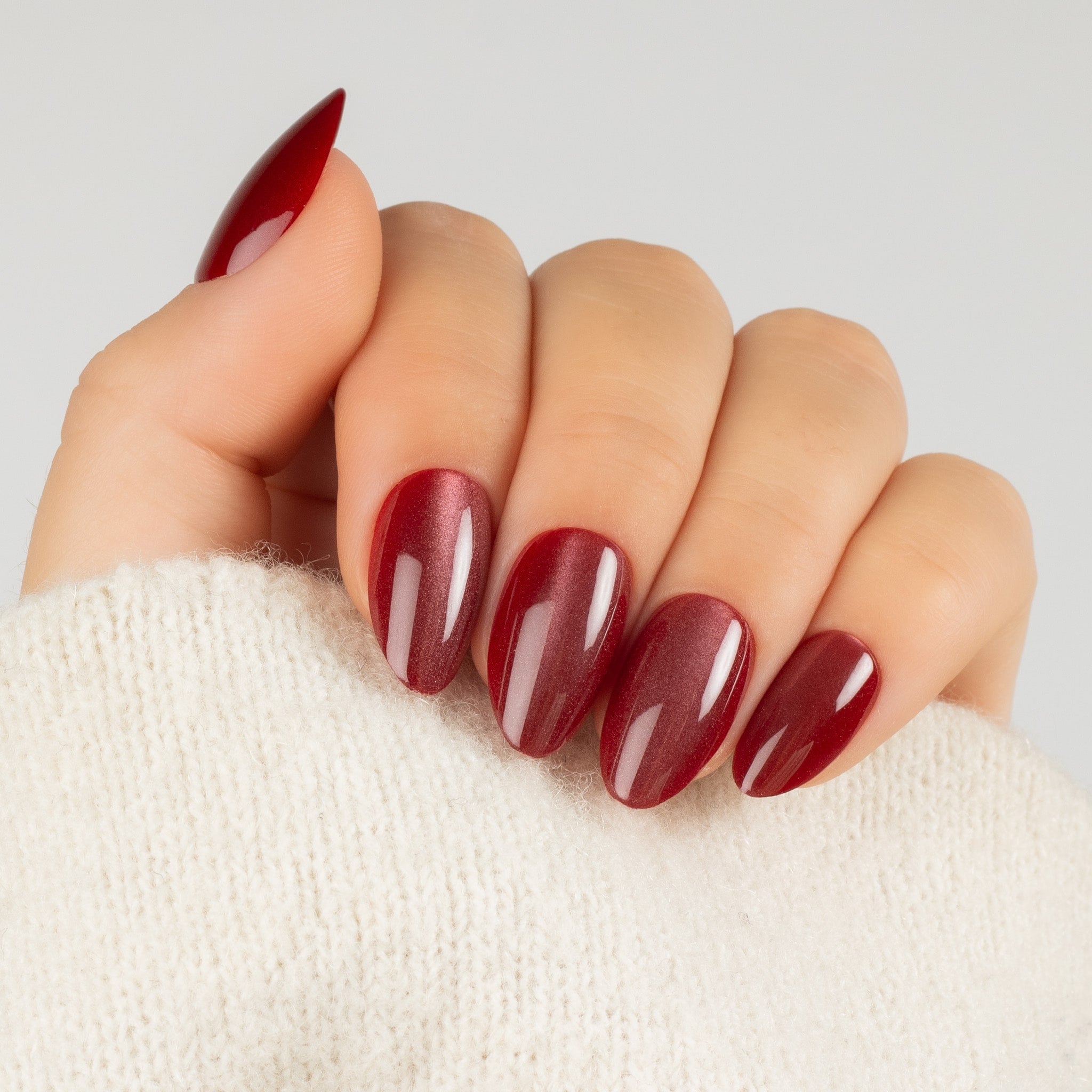 Cat Eye ruby Almond – vinröda skimrande press-on naglar i almond-form på hand